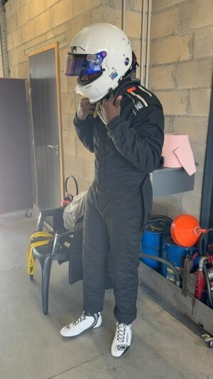 La préparation, le rituel. Sur le casque blanc, le drapeau de la RDC — visible à chaque course.