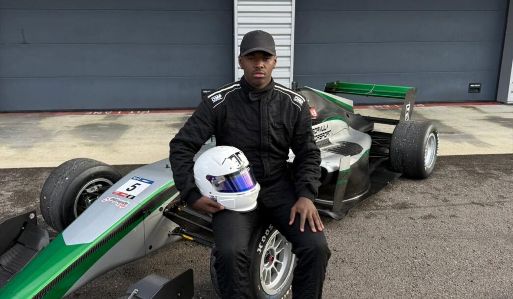 Tjay assis sur sa F3 verte #5,casque à la main, regard caméra