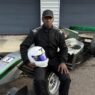 Tjay assis sur sa F3 verte #5,casque à la main, regard caméra